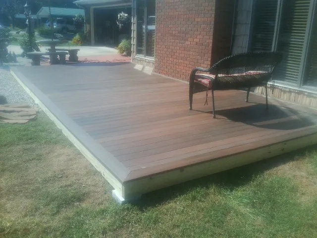 New wood deck and wicker chair beside a brick house in Skykomish