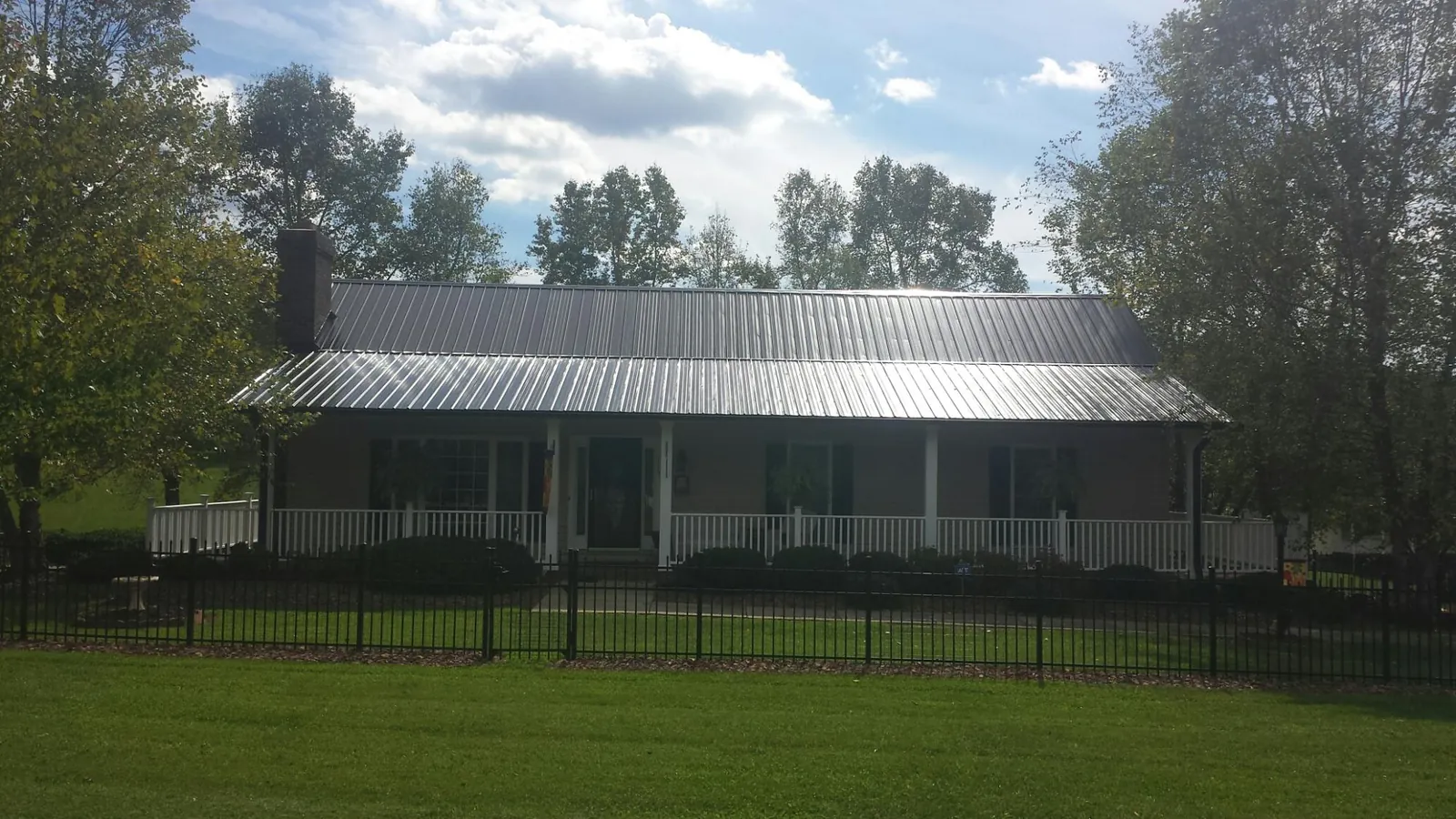 Gray metal roof on a brick ranch with a full width front porch — Gutter Guard Installation work by our crew in Skykomish