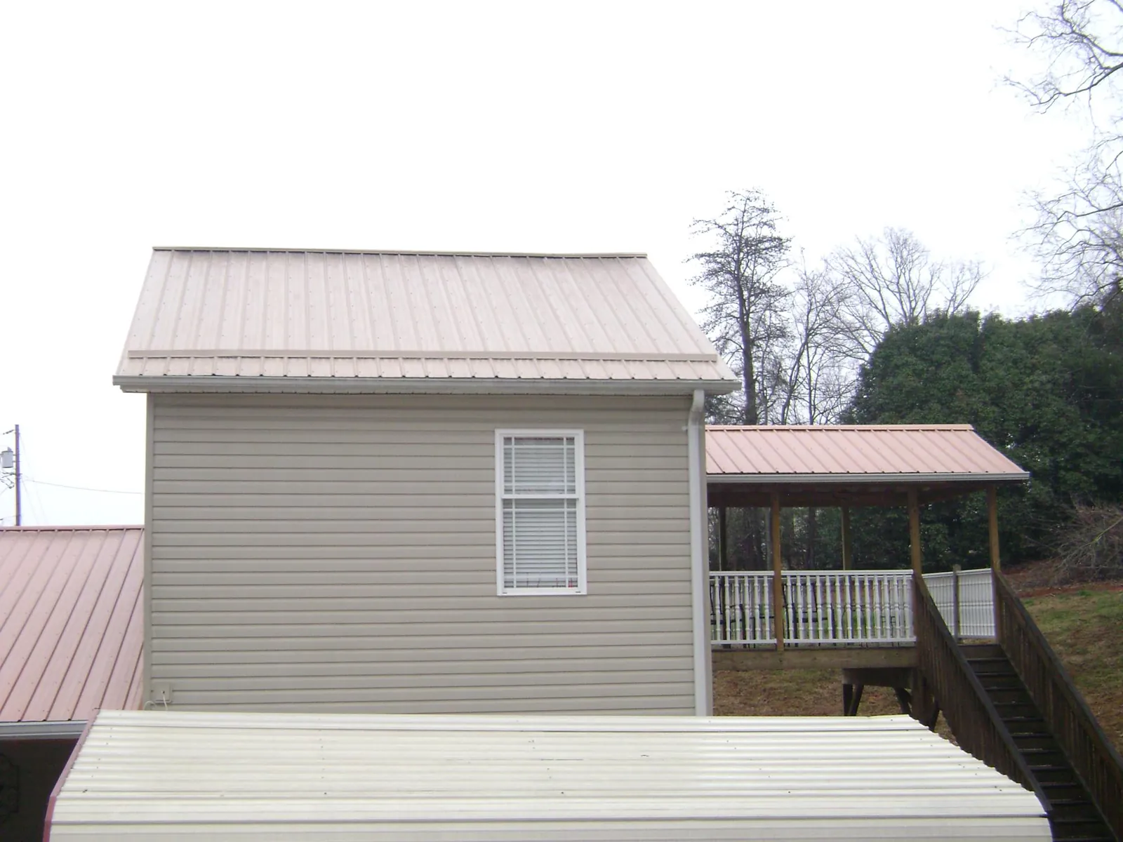 Tan metal roofs on a two story addition and attached porch, from a Roof Replacement job in Skykomish