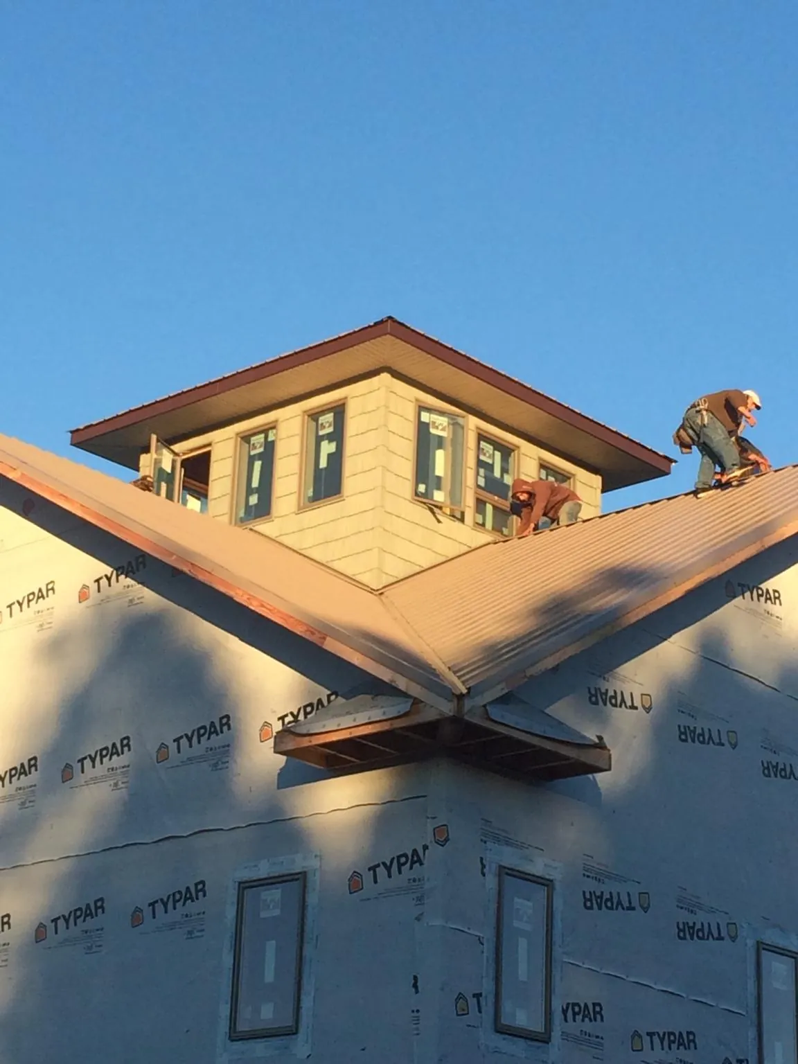 Roofers working around a rooftop cupola on a new metal roof at sunset — Roof Waterproofing in Skykomish by Roofing Brothers